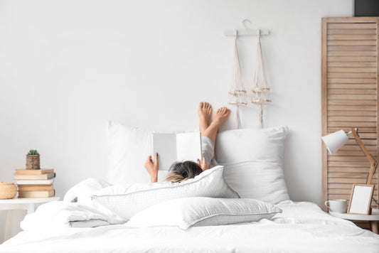 Morning of young woman reading book in bed.