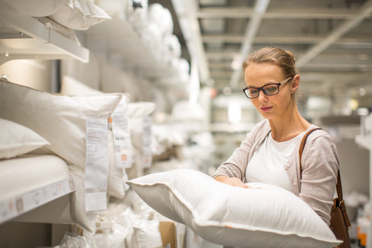 Pretty, young woman choosing the right pillow for her bed in a modern home furnishings store